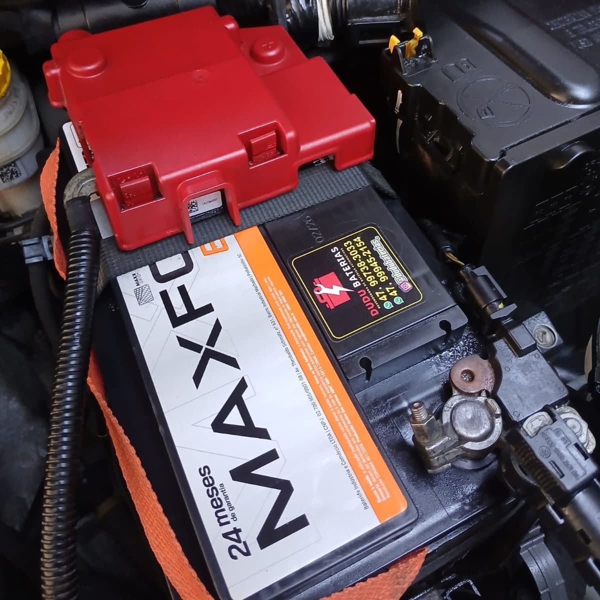 Bateria Maxforce recém-instalada no motor, com o adesivo de contato da Dudu Baterias