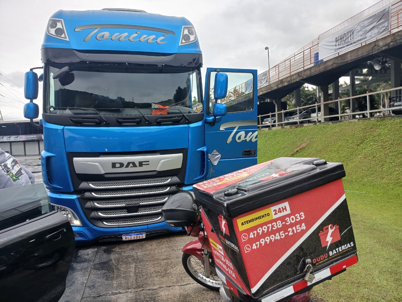 Atendimento da Dudu Baterias a um caminhão DAF, com a moto de entrega ao lado